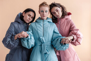 Fashion style studio portraits of beautiful woman posing in winter vogue stylish design coats on creamy pastel background.