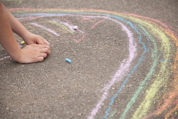 The child draws with chalk on the pavement. Children's creativity.