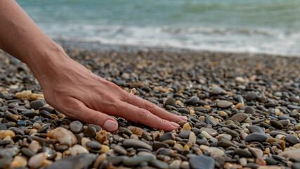 Ring on the sea, on the hand put on a sea ring of water, on the beach of stones, the hand of a beautiful female, a shell in the form of decoration