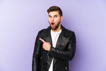 Young man isolated on purple background pointing to the side