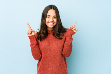 Young mixed race hispanic woman isolated indicates with both fore fingers up showing a blank space.