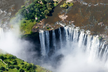 Aerial view of Victoria Falls with an impressive volume of water flowing. Water mist from waterfall...
