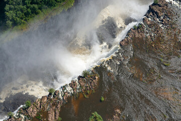 Aerial view of Victoria Falls. Water stream flowing down a canyon with a rainbow.  Helicopter...