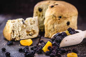 measuring wooden spoon with candied fruit, raisin and apricot, with panettone unfocused in the...