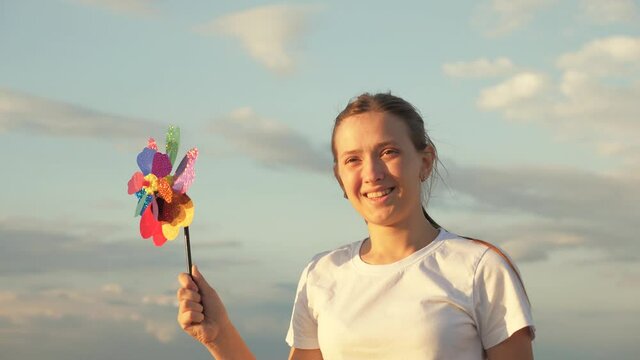 Happy child playing having fun pinwheel. Happiness vacation childhood happy family holiday. teen girl playing pinwheel park in slow motion. childhood concept. child playing in park catches wind