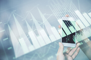 Double exposure of forex graph sketch hologram and woman holding and using a mobile device. Stock market concept.