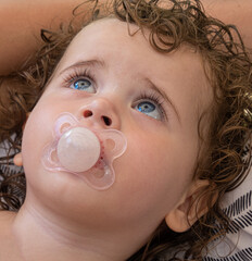Baby girl using pacifier looking to the sky