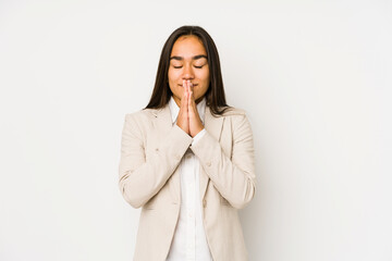 Young woman isolated on a white background holding hands in pray near mouth, feels confident.