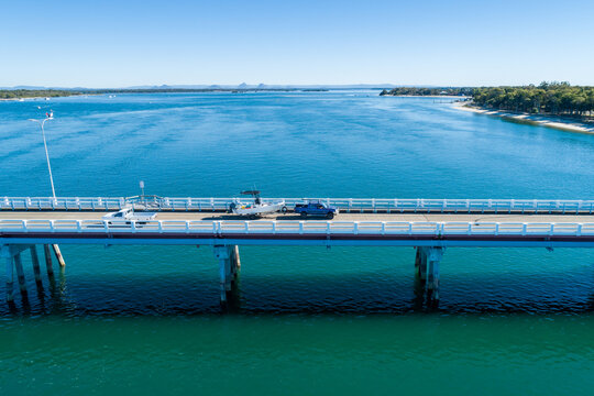 Blue ute towing a fishing boat on bridge over water.