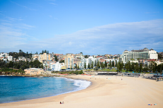 Beach that is almost empty, with buildings and trees in the background