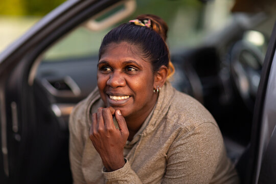 Head And Shoulders Of Woman With Hand Touching Chin Leaning Out Of Open Passenger Door Of Car