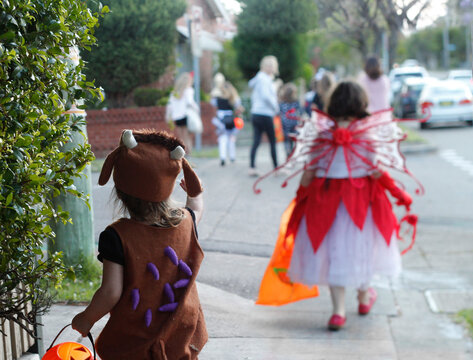 Children dressed in costumes walking along the street, trick or treating