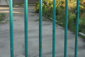 green metal texture of iron bars in the pattern in the wall of the fence on the street