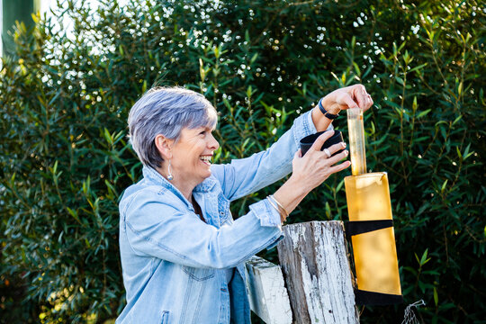 Senior woman checking rain gauge on fence