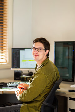 Young male uni student studying on computer at desk