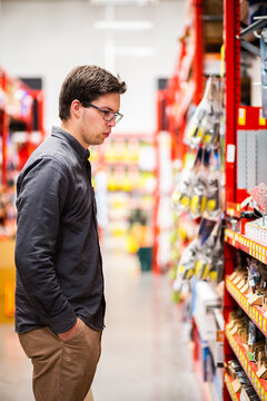 Young man in hardware store looking at tools