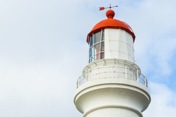 Close up of the top of a lighthouse with a red roof