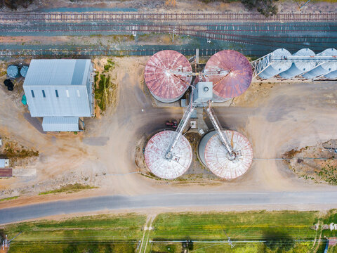 Looking down onto grain silos beside a road and railway line