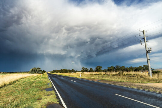 Looking down a country road towards a large thunderstorm