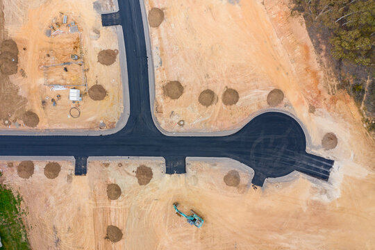 Aerial view of roads and house blocks and machinery in a new housing subdivision