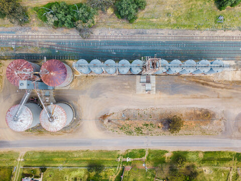 Aerial view of a row of grain silos between a road and railway line