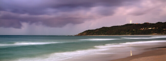 An evening storm approaching a headland with a lighthouse on top