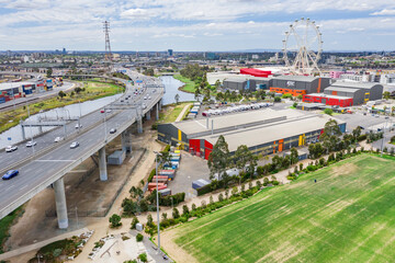 Aerial view of a wide freeway overpass with a sporting field below and ferris wheel in the distance