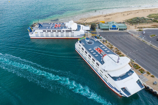 Two car ferries anchored at a terminal near a beach