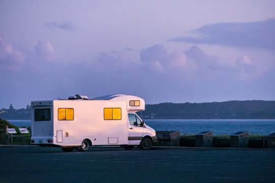 A campervan parked at an ocean lookout at twilight