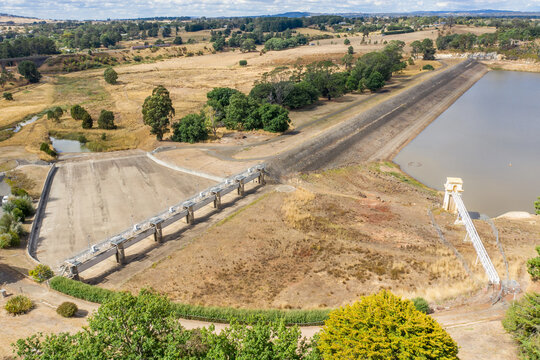 Aerial view of a reservoir and dam wall with a dry spillway.