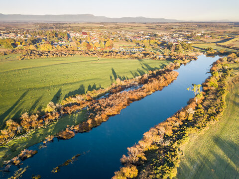 Aerial view of golden trees lining the banks of a river in Autumn
