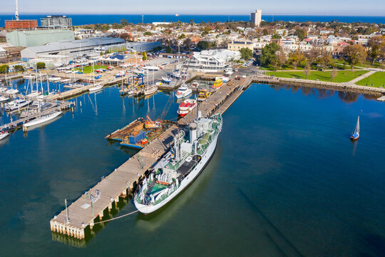 Aerial view of a naval ship at a dock at a bay side harbour