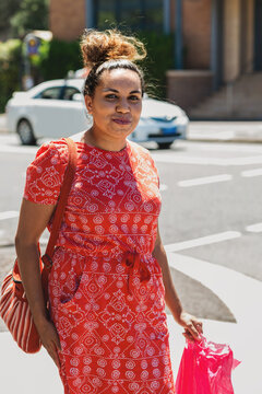 aboriginal woman walking on the footpath with a shopping bag