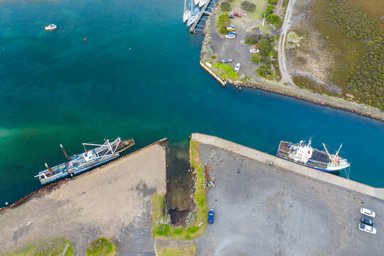 Aerial view of a fishing boat and a dredge docked in a coastal channel