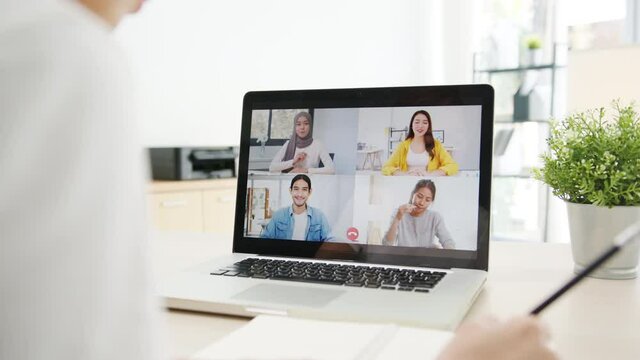 Asia businesswoman using laptop talk to colleagues about plan in video call meeting while working from home at living room. Self-isolation, social distancing, quarantine for corona virus prevention.