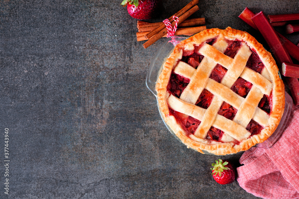 Poster strawberry rhubarb pie. overhead view corner border against a dark stone background with copy space.