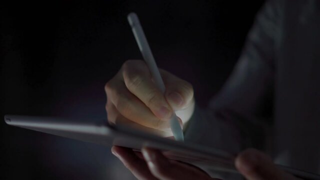 4K Video close up man hand using pen on tablet with black background. Concept for tablet technology and touchscreen.