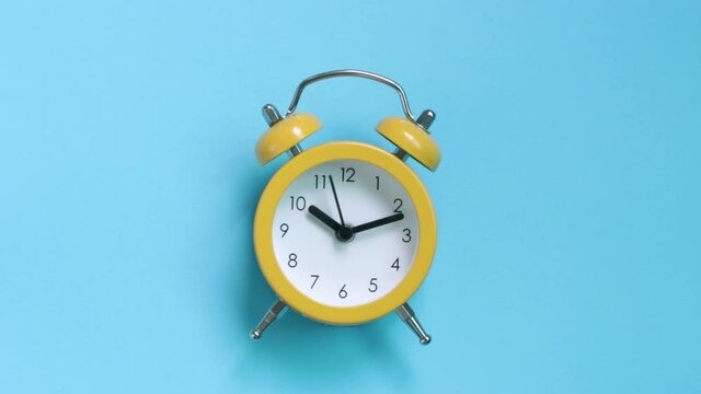 Yellow alarm clock on a blue background close-up, top view