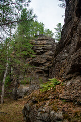 
Stone mountains. 
Stone texture. Mountain gorge. Among the huge rocky mountains there is a mountain river, the mountains are covered with fresh bright green foliage of trees in early spring.
