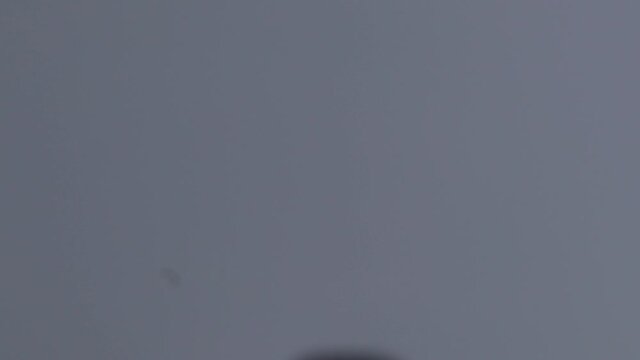 Footage of kite festival in India where a young boy is trying to fly a yellow kite on his roof with selective focus.