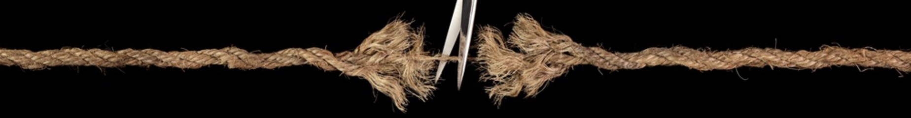 Rope ready to break apart held together by a last strand with scissors ready to cut it apart. Concept of dangerous stress or stressful situation like ominous threats, failure, or tension.