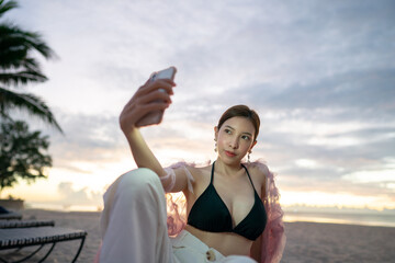 Asian woman take a selfie on the beach at sunrise scenery.