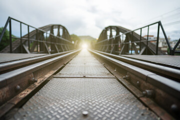 Vintage railroad, railway tracks on bridge in a rural scene with golden light at the end destination.