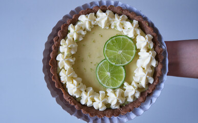 key lime pie. lime pie and whipped cream with sablé dough and garnished with slices and lime zest