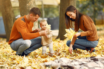 Family in a autumn park. Woman in a brown sweater. Cute little girl with parents.