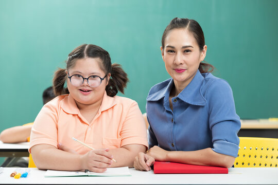 portrait asian disabled child or down syndrome child and woman teacher helping in classroom