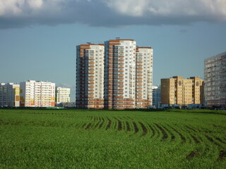 Multi-storey building in a green field against a blue sky and clouds