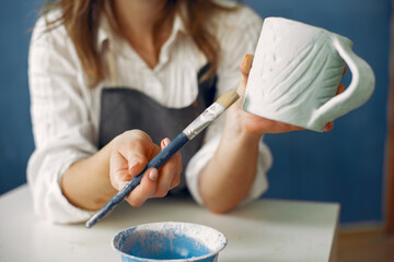 Woman in a pottery. Master paint a dishes. Artist works with a clay. Ceramics theme.