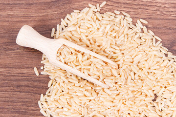 Brown rice with wooden scoop on board, healthy nutrition
