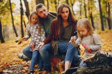 Family in a autumn park. Woman in a red sweater. Cute childrens with parents